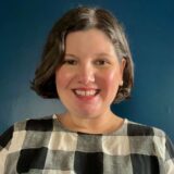 Portrait photo of Anita Carter, white woman with short brown hair, wearing a black and white checkered blouse.