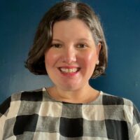 Portrait photo of Anita Carter, white woman with short brown hair, wearing a black and white checkered blouse.