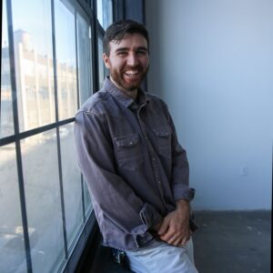 Portrait photo of man standing by a window and looking at the camera.