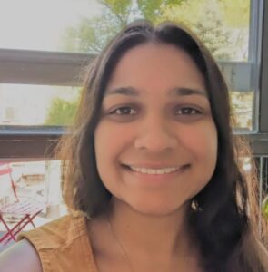 A person with long dark hair smiles at the camera