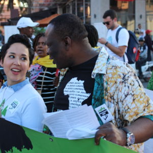 : Corporate Accountability’s International Policy Director, Tamar Lawrence-Samuel, and Godwin Ojo, co-founder and programmes director of Environmental Rights Action/Friends of the Earth, Nigeria, march together during the 2016 U.N. climate change treaty meetings in Marrakech, Morocco.
