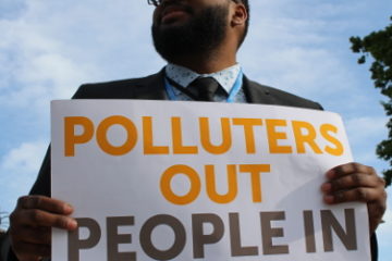 Protester holds "Polluters out, people in" poster
