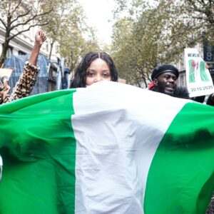 Woman in London holds up a Nigerian flag, standing in solidarity with the #EndSARS movement.