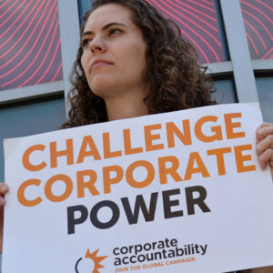 Corporate Accountability organizer holds sign that reads "Challenge Corporate Power