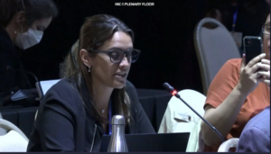 Agustina Luque from the Latin America Healthy Coalition (CLAS) speaks into a microphone to deliver a statement calling for corporate accountability at the UN plastics treaty negotiation.