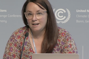 Rachel Rose Jackson on a UNFCCC Bonn panel organized by the Global Campaign to Demand Climate Justice. She speaks into a microphone with a computer in front of her.