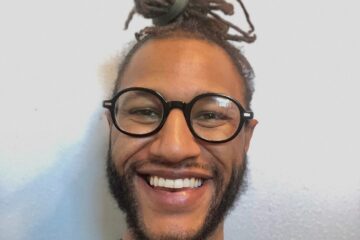 Portrait photo of Med Diangne, membership organizer. Med has dark skin, a light beard, and long hair that's tied back, and black-rimmed glasses.