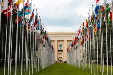 United Nations in Geneva on a cloudy day, flags stretch out across the bright green lawn.