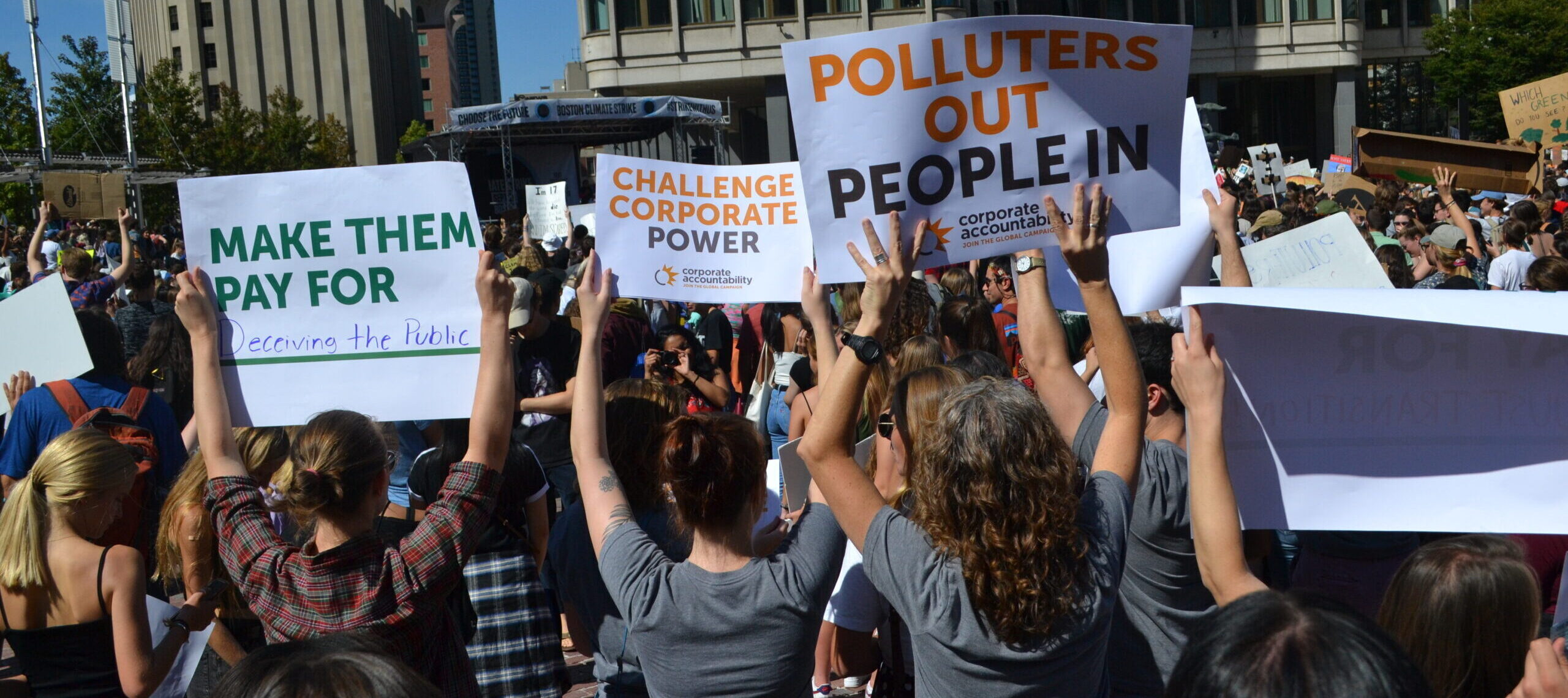 Protesters holding signs that read "Polluters out, people in"