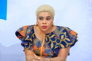 Zikora Ibeh, board member, wears a blue and orange top with intricate flower prints and gold hoop earrings.