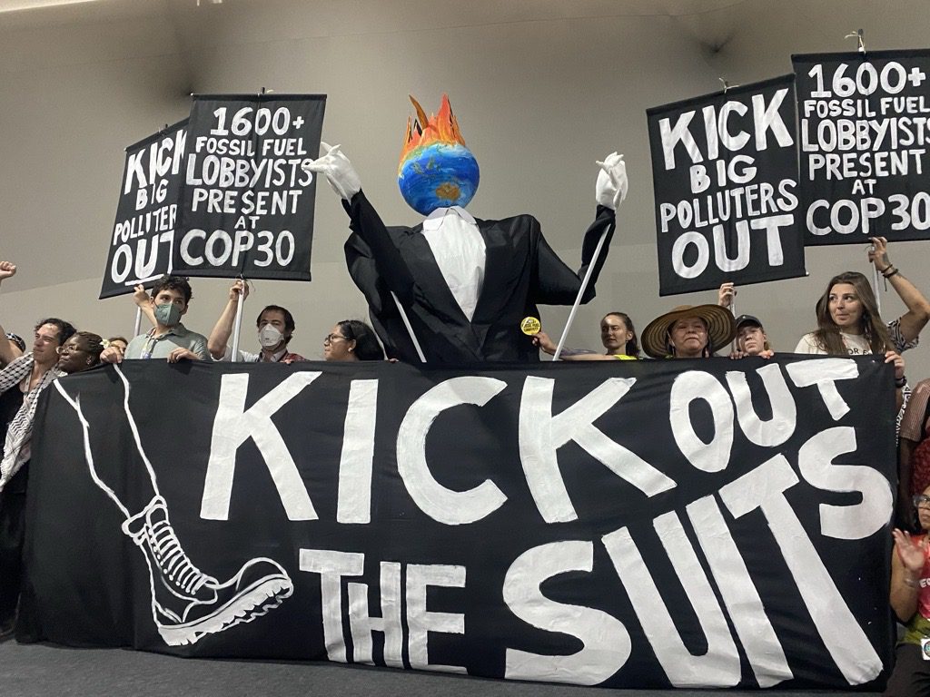 Protest with a giant sign reading "Kick out the suits"